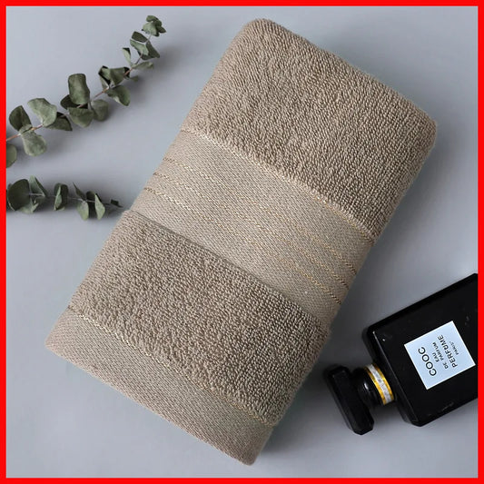 Beige towel on a gray surface with a bottle and eucalyptus leaves.
