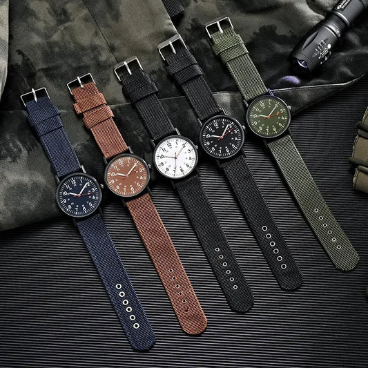 Five watches with different colored straps on a textured surface