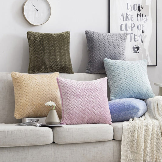 Colorful knit pillows on a sofa with a clock and framed picture in the background.