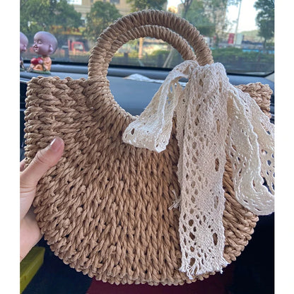 Woven handbag with lace detail held by a person, blurred background
