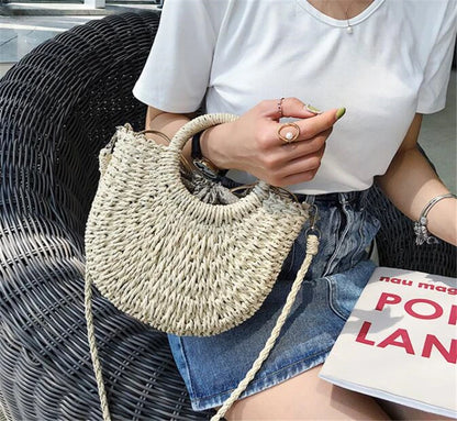 Person holding a woven handbag sitting on a chair with a magazine.