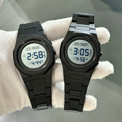 Two black digital watches on a light gray surface with a white cloth underneath.