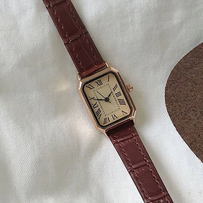 Watch with a brown strap and gold case on a white background