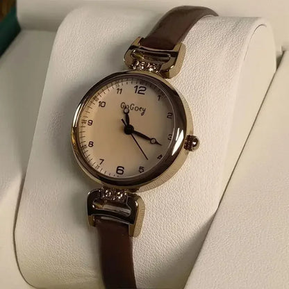 Watch with a brown strap on a white cushion