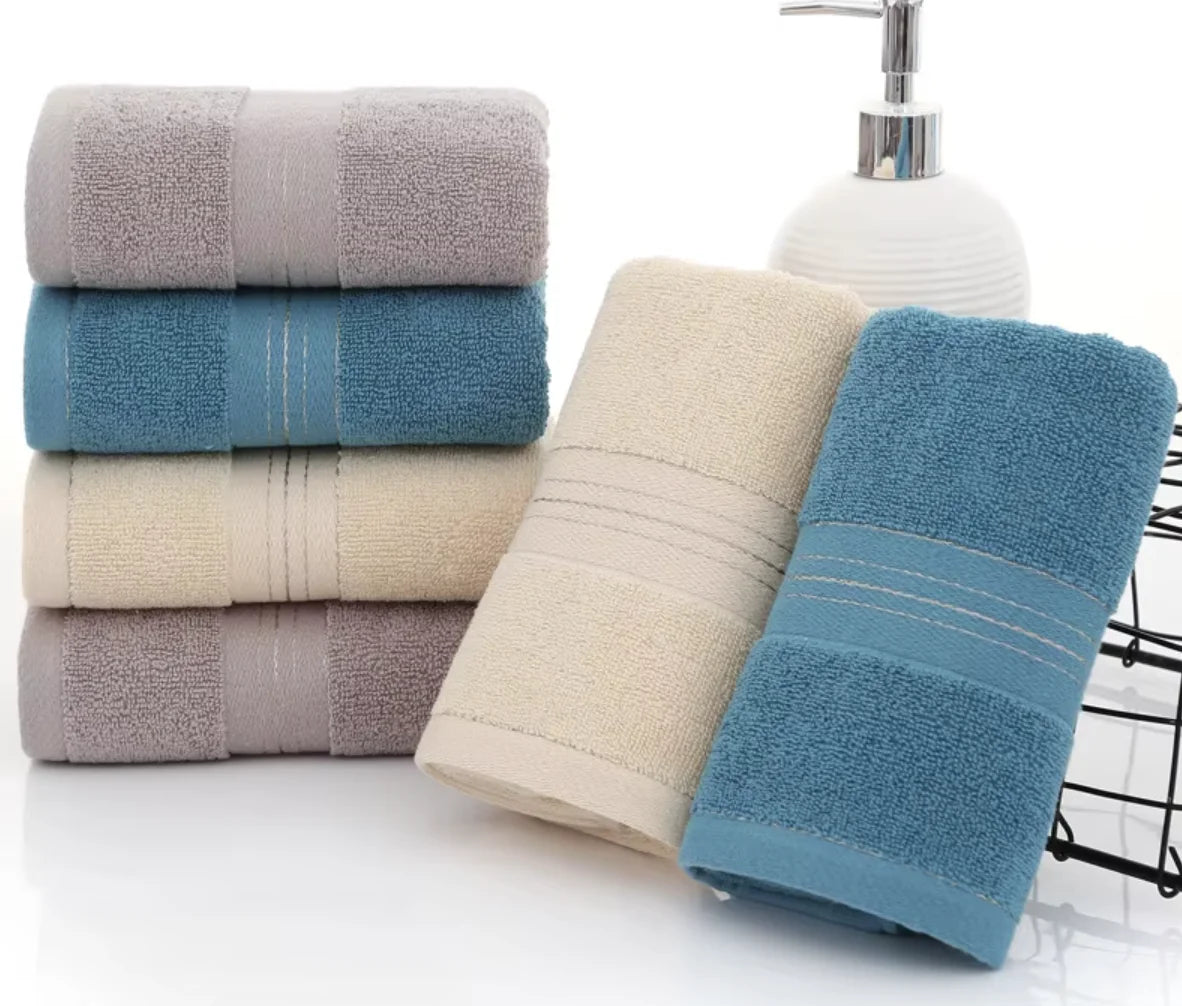 Stack of folded towels in blue, beige, and gray with a soap dispenser on a white background