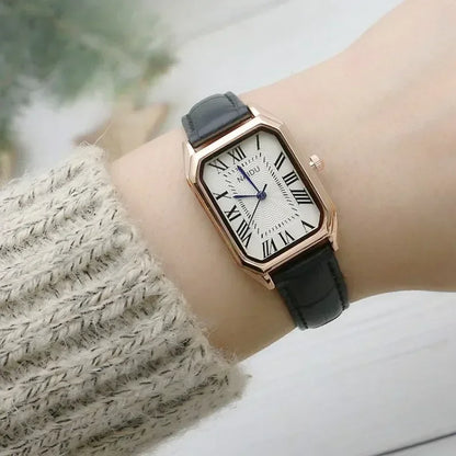Wristwatch with black strap and rose gold case on a wrist, blurred background