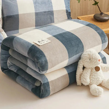 Folded plaid blanket with a tag on a couch next to a plush toy