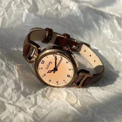 Wristwatch with a gold case and beige strap on crumpled paper