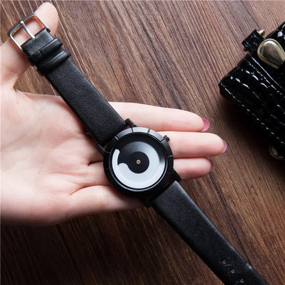 Black wristwatch with a unique face held in a hand on a wooden surface