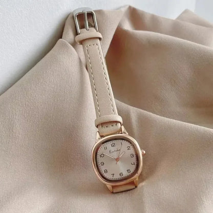 Wristwatch with a beige strap on a beige fabric background