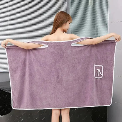 Person holding a large purple towel with a logo in a bathroom setting