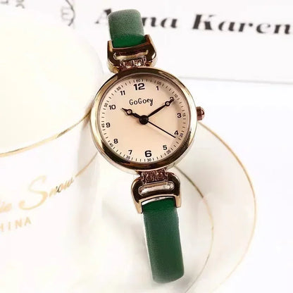 Green wristwatch with a beige face on a white surface