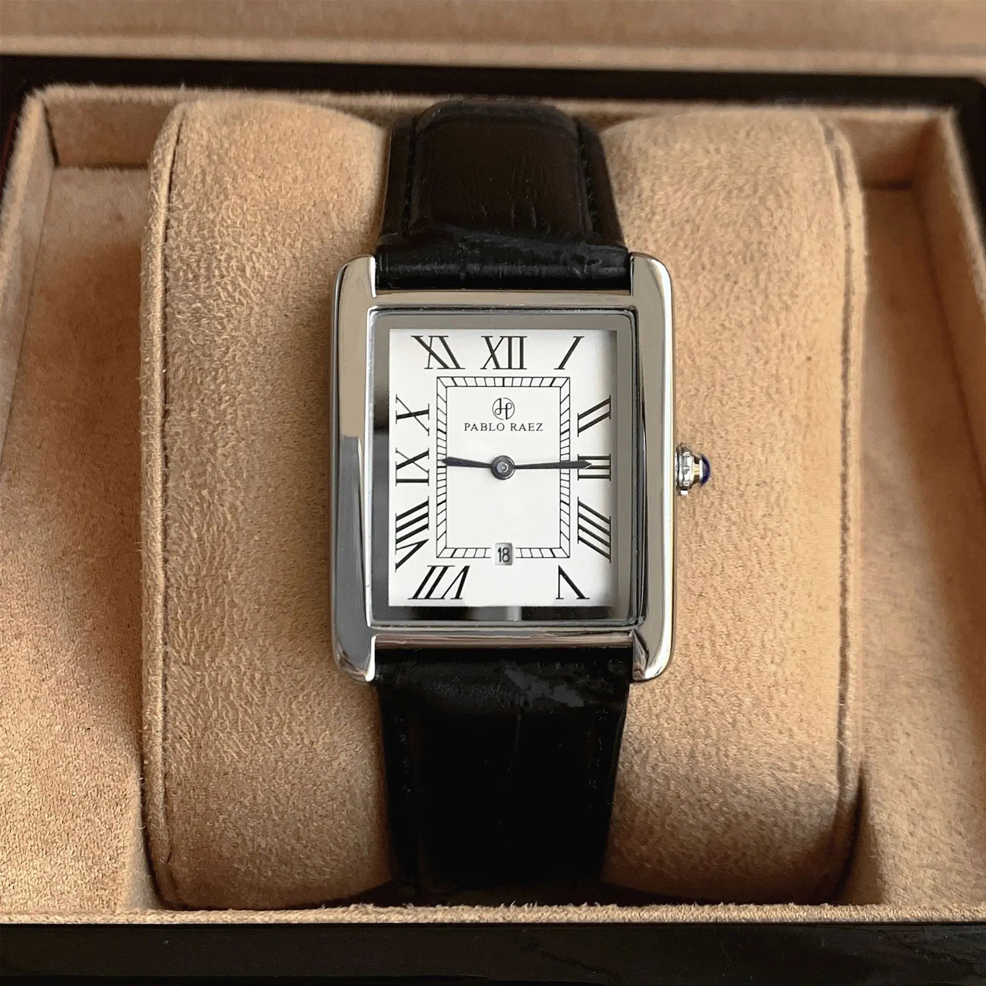 Watch with black strap and silver case on beige cushion in a box