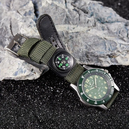 Green watch with compass attachment on a rocky surface