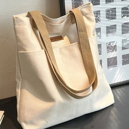 Beige tote bag with brown straps on a reflective surface