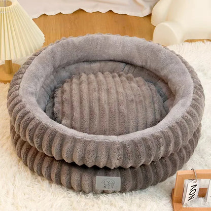 Gray pet bed on a white surface with a lamp and chair in the background