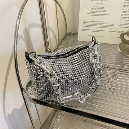 Silver handbag with chain details on a glass surface