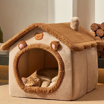 Cat lying inside a plush pet house with bear ears and a chimney.