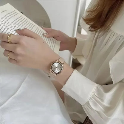 Person wearing a gold watch reading a book, with a neutral background
