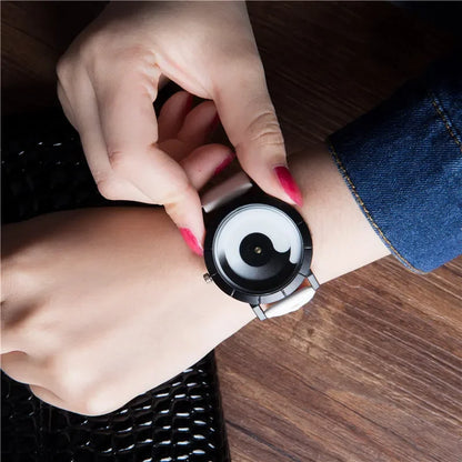 Person wearing a black and silver watch on a wooden surface