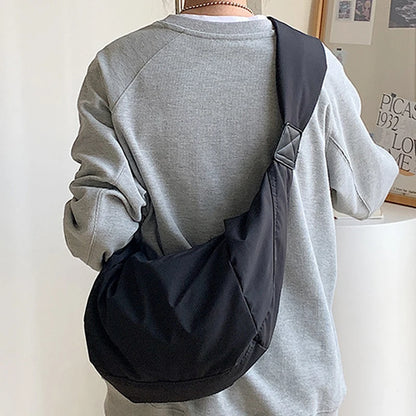 Person wearing a gray sweatshirt with a black backpack on a plain background