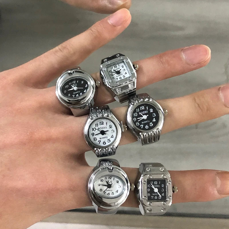 Multiple watches on a person's fingers against a neutral background