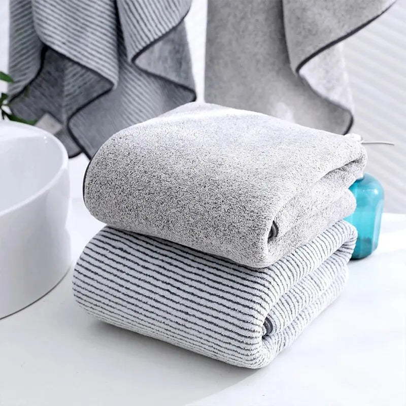 Stack of gray towels on a bathroom counter with a towel rack in the background.