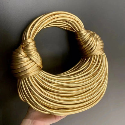 Gold woven ring held against a dark background