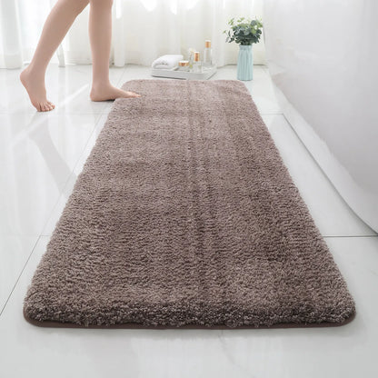 Brown bath mat on a bathroom floor with a person stepping onto it.