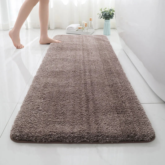 Brown bath mat on a bathroom floor with a person stepping onto it.