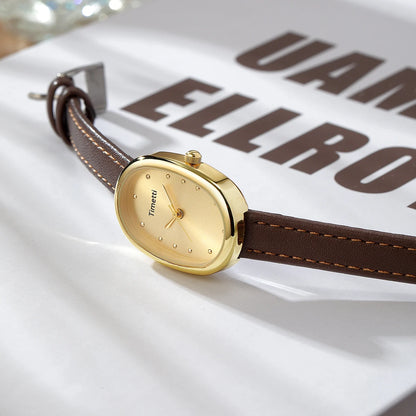 Gold watch with brown strap on a white surface