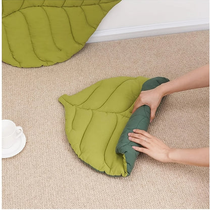 Green leaf-shaped cushion being adjusted on a beige carpet