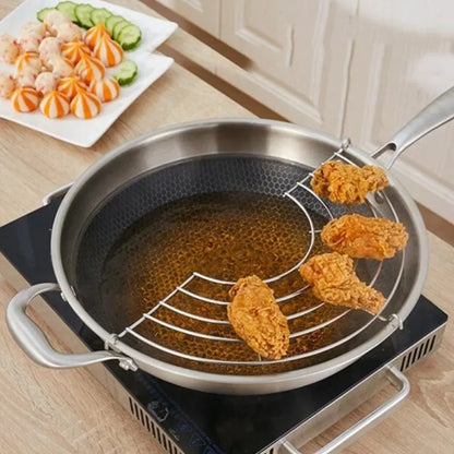 Fried chicken pieces being cooked in a frying pan with a metal rack.