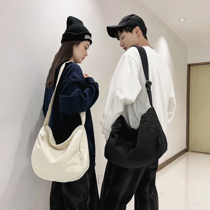 Two people standing indoors, each holding a bag, wearing casual clothing.