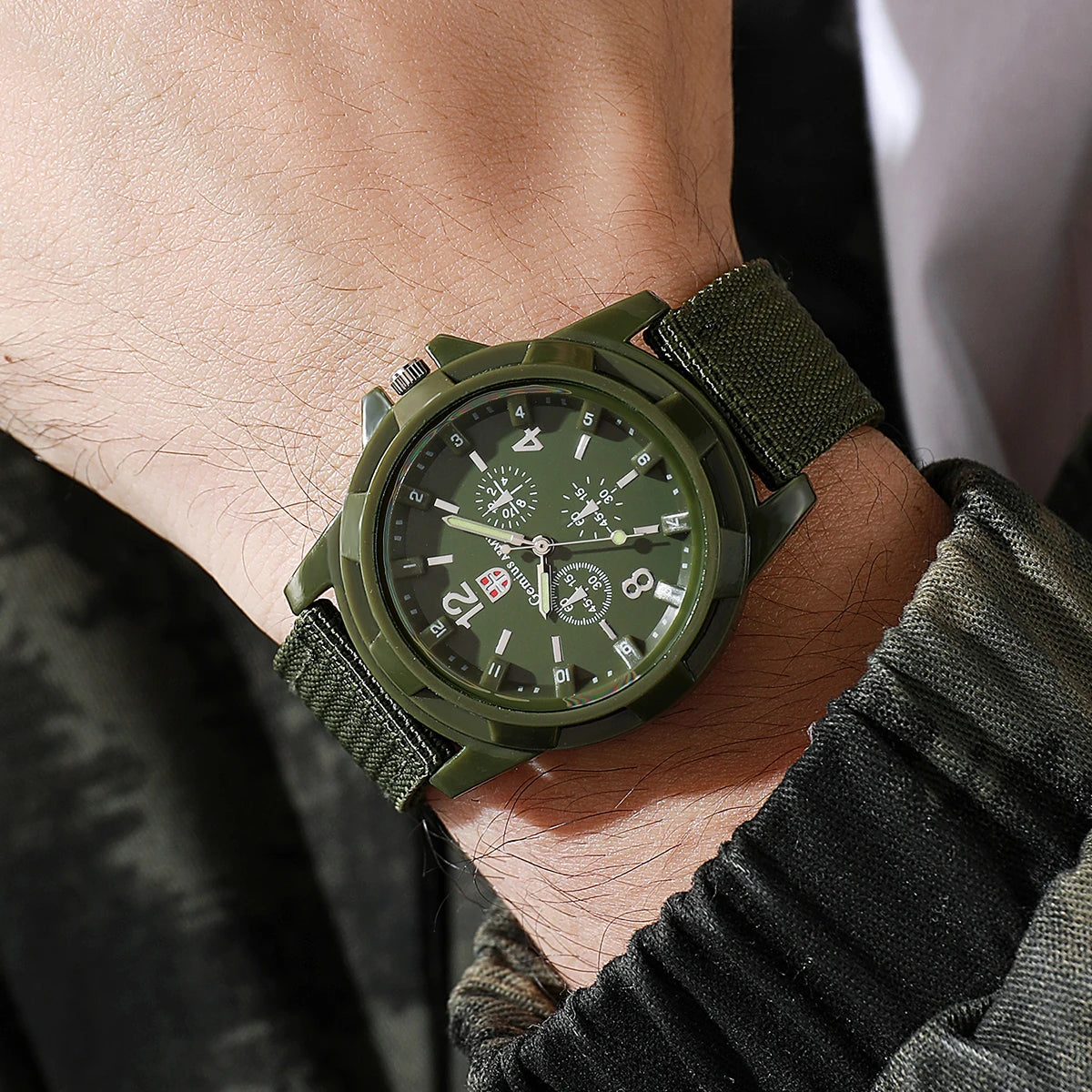 Green military-style watch on a wrist with a blurred background