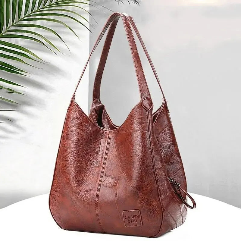 Brown leather handbag on a white surface with a light background