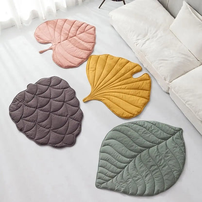 Four leaf-shaped mats in pink, yellow, gray, and green on a light surface.