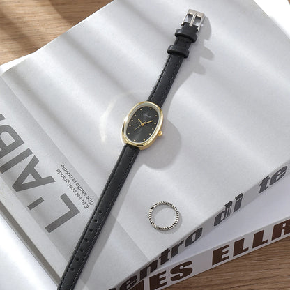 Watch with black strap and gold face on a magazine