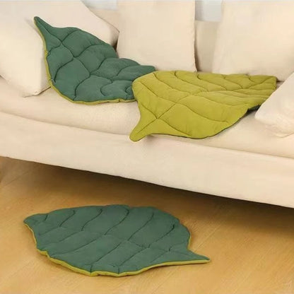 Leaf-shaped green and yellow cushions on a beige sofa and floor.