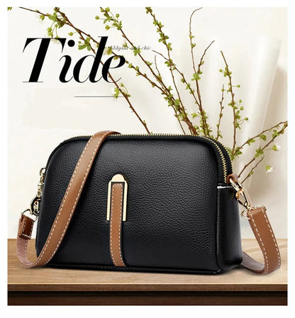 Black handbag with brown straps on a wooden surface with 'Tide' branding.
