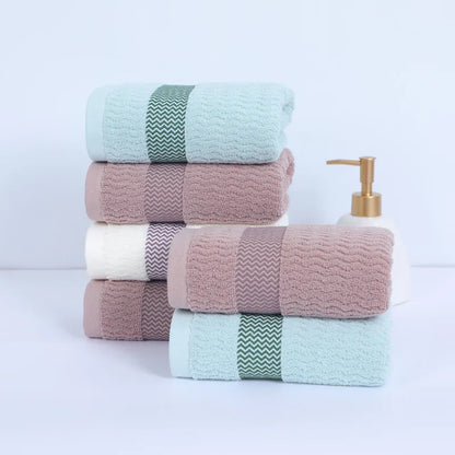 Stack of colorful towels with a soap dispenser on a light background