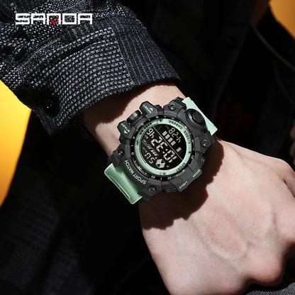 Digital watch with green strap on a wrist, brand 'SANDA' visible