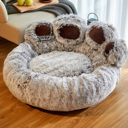Fluffy pet bed with paw-shaped ends on a wooden floor.