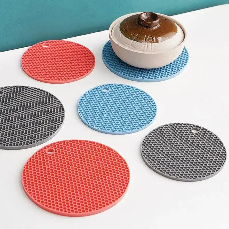 Set of colorful silicone trivets on a white surface with a teal background