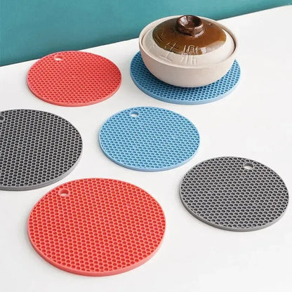 Set of colorful silicone trivets on a white surface with a teal background