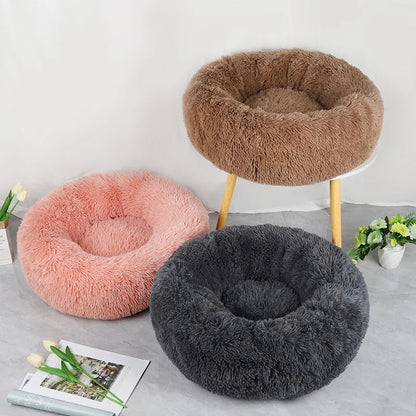 Three fluffy pet beds in brown, pink, and gray on a light gray surface with a white background.