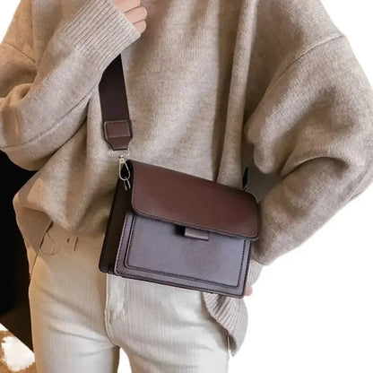Person wearing a brown sweater and holding a brown leather bag.