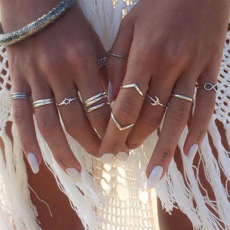 Close-up of hands wearing multiple gold rings with a white lace background