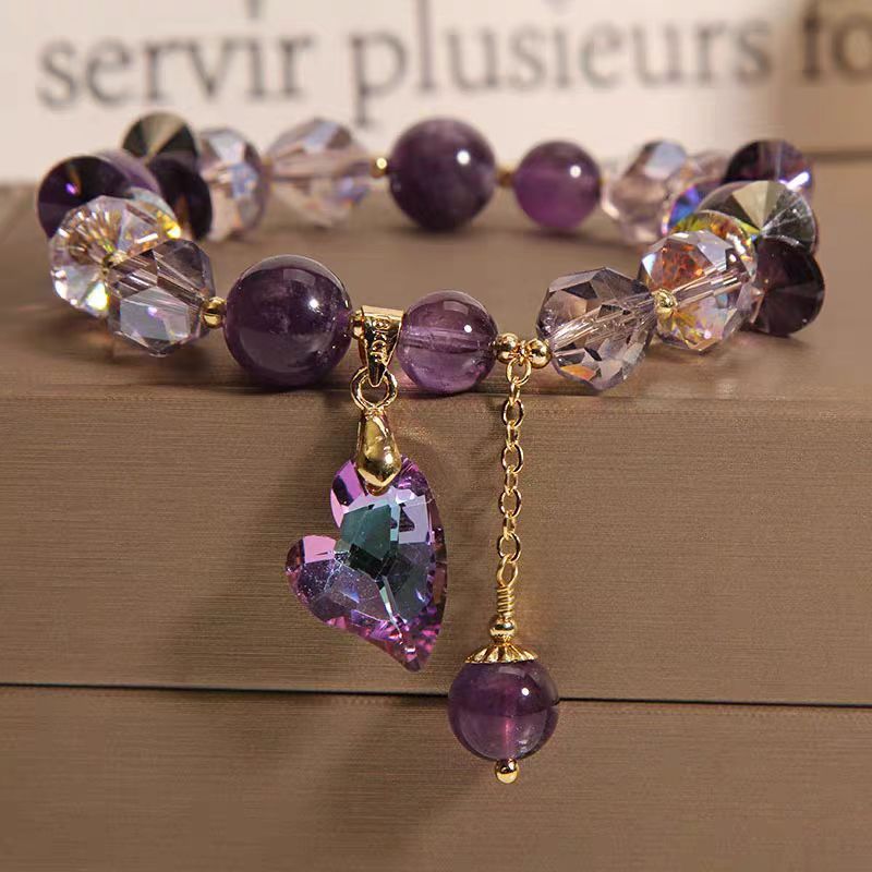 Bracelet with purple beads and a heart-shaped charm on a wooden surface